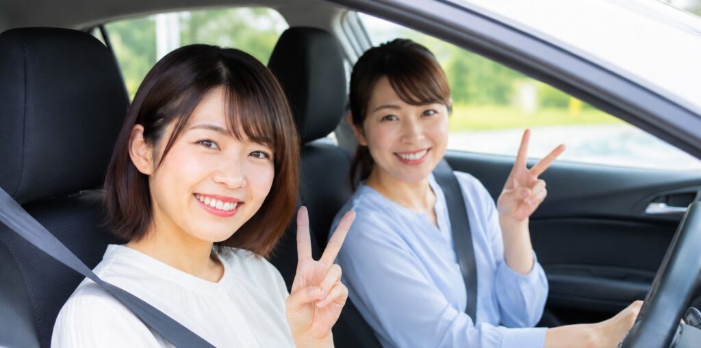 ペーパードライバー講習後に笑顔で車内に座る女性と指導員